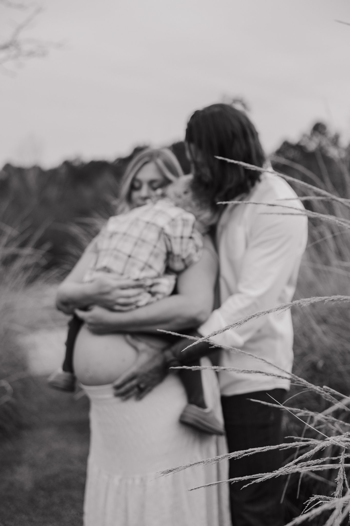  Maternity portrait of an expecting mother in an open field at NCMA Park in Raleigh, NC, celebrating her second pregnancy in soft natural light. 