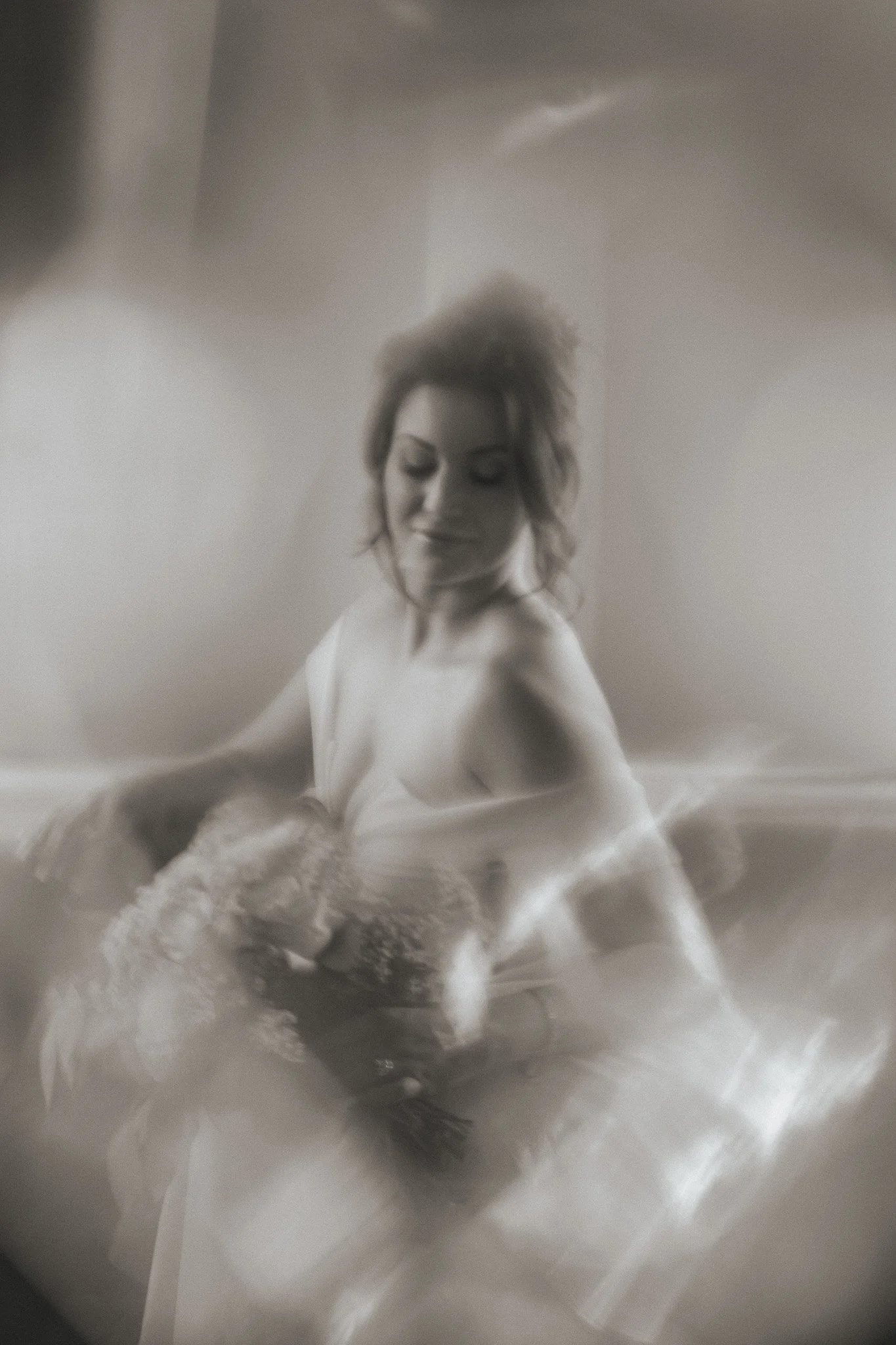 Abstract black and white photo of a woman in a dress holding a bouquet, with blurred motion effect.