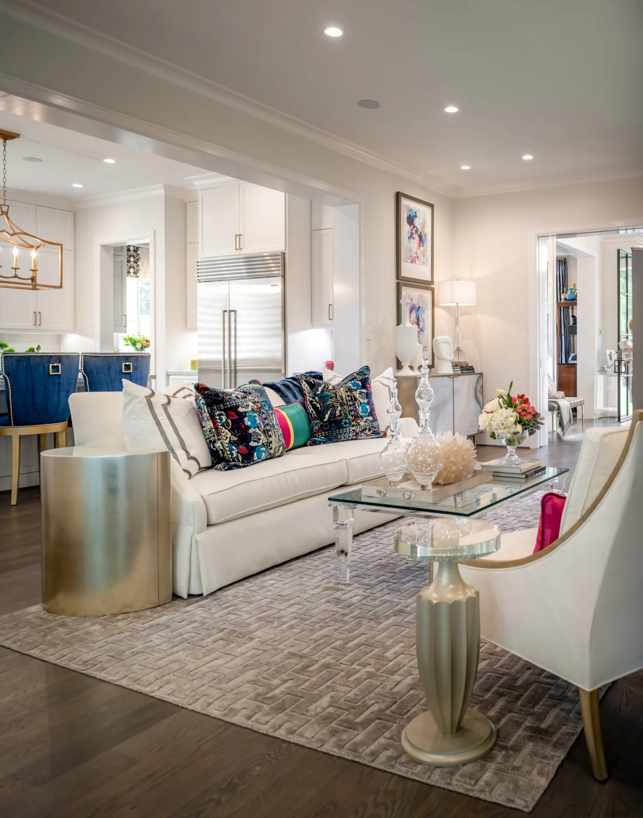 Elegant River Oaks living room designed by The Design Firm in Houston, featuring a white sofa, colorful accent pillows, glass coffee table, and custom furnishings.