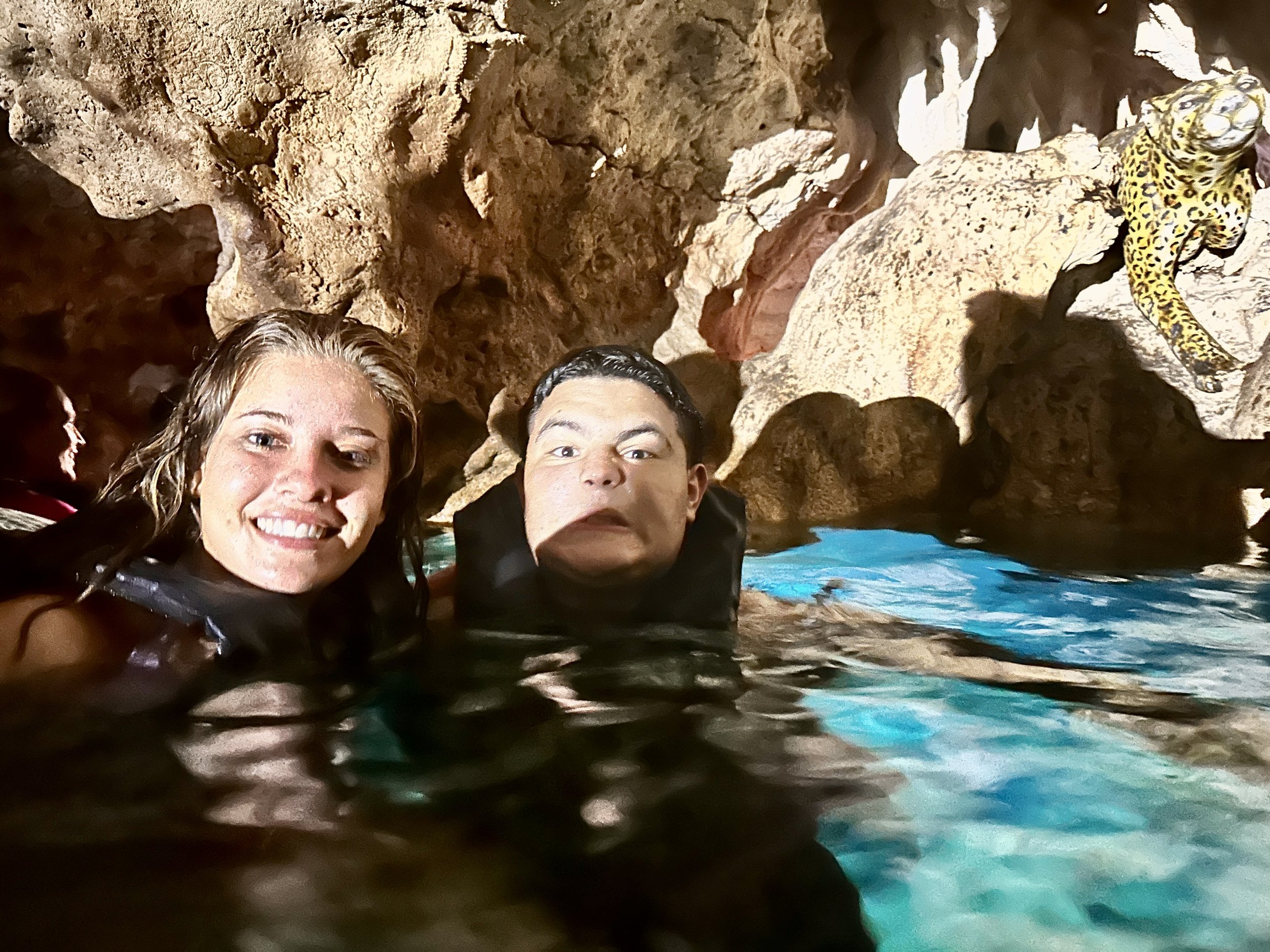 Two people smiling in a cave pool