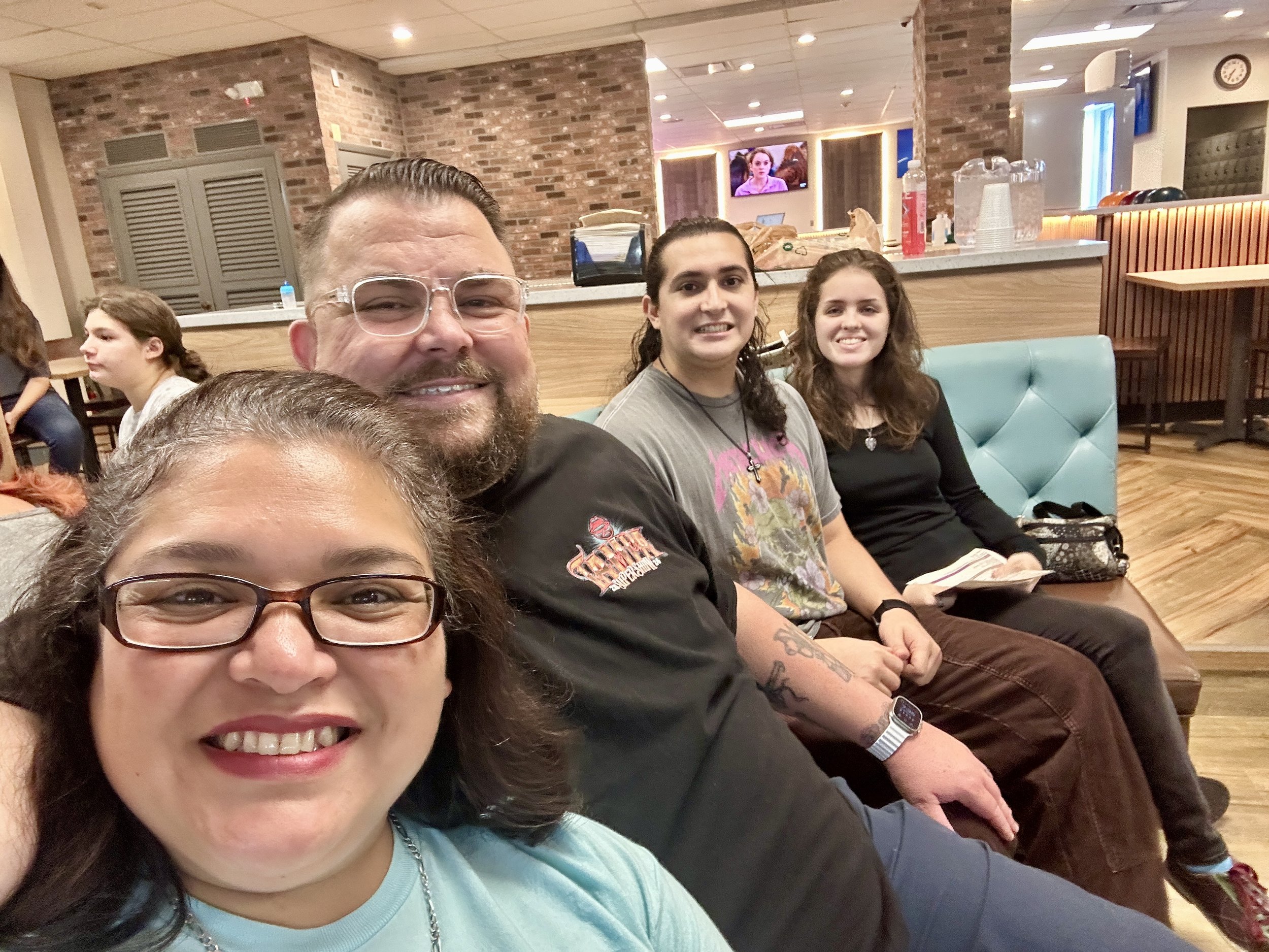 Group of people smiling inside a restaurant or cafe with brick walls and modern decor.