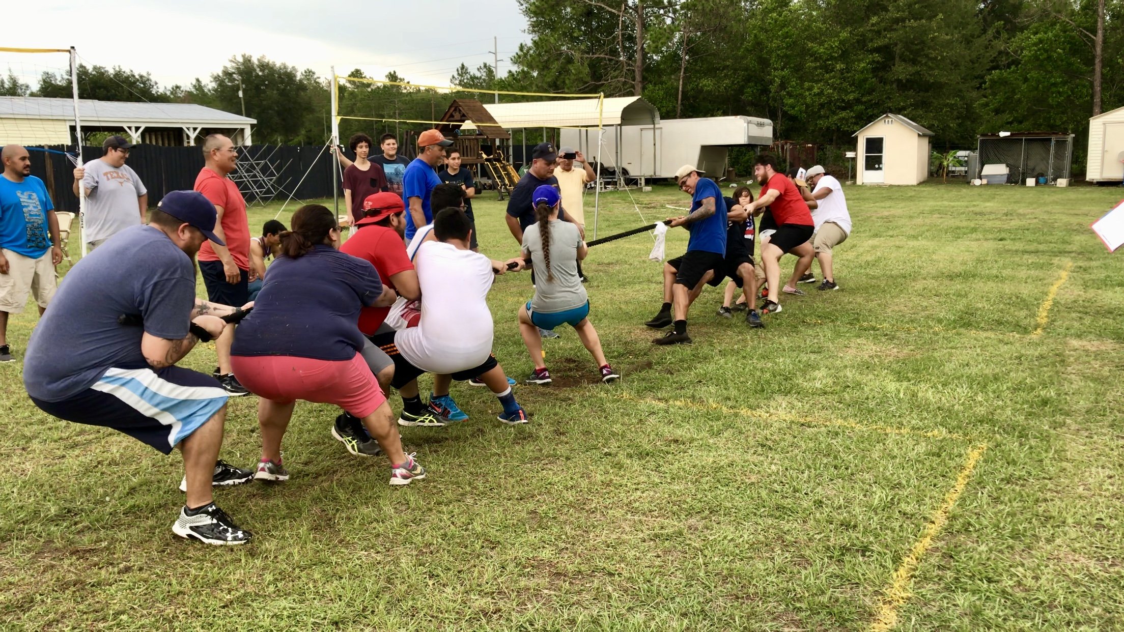 Group of people playing tug-of-war on a grassy field