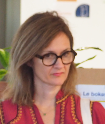 Personne portant un pull orange, haut du corps visible, regardant vers la droite.