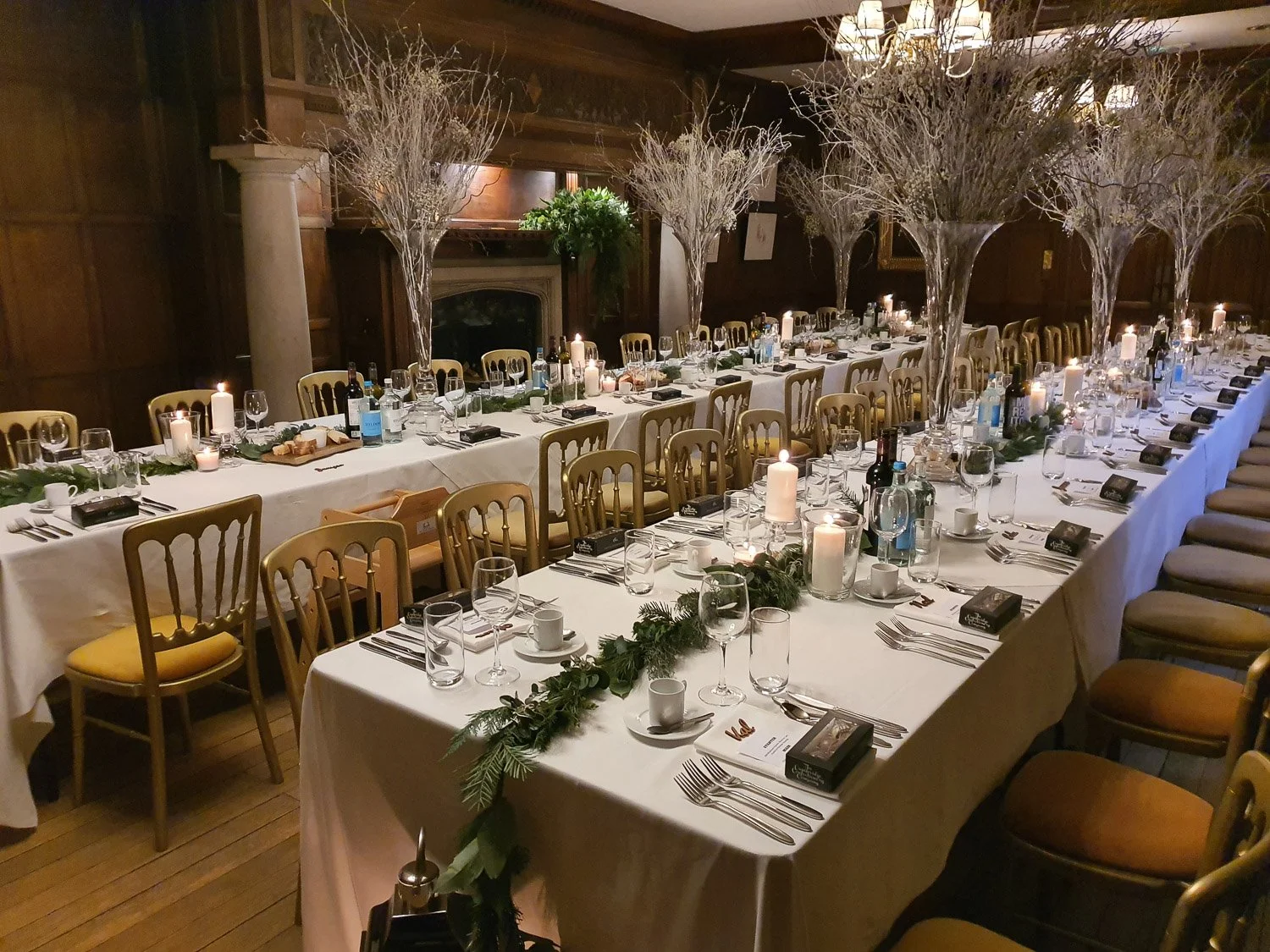 Festive Christmas dinner setup at Lanwades Hall, Suffolk, featuring candlelight, winter foliage, and elegant long tables in the wood-panelled hall.