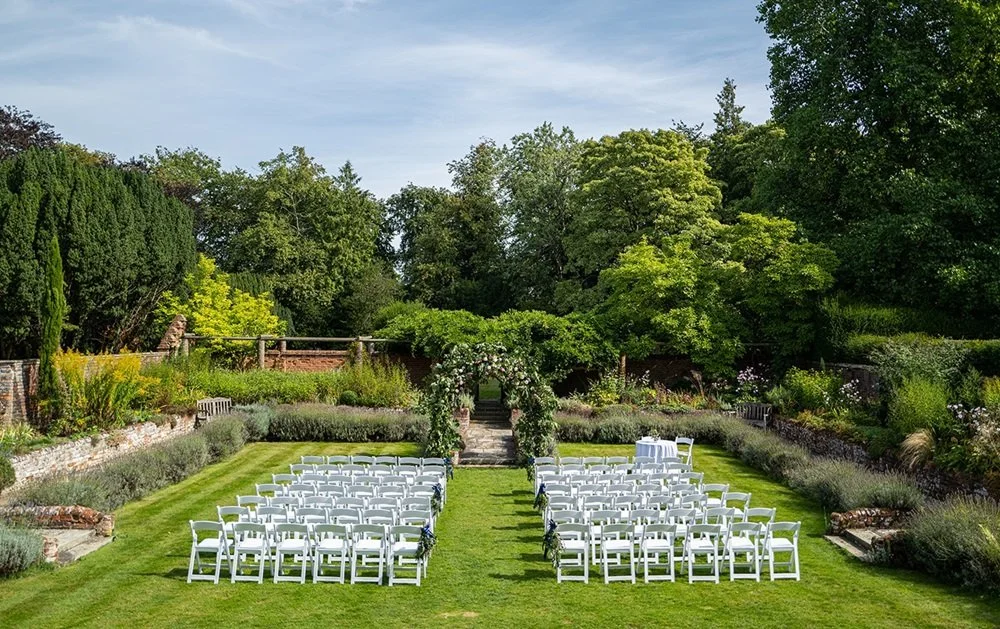Outdoor wedding ceremony set-up in the Sunken Garden at Lanwades Hall, Suffolk, surrounded by lush lawns and a stone terrace — perfect for al-fresco ‘I do’s’.