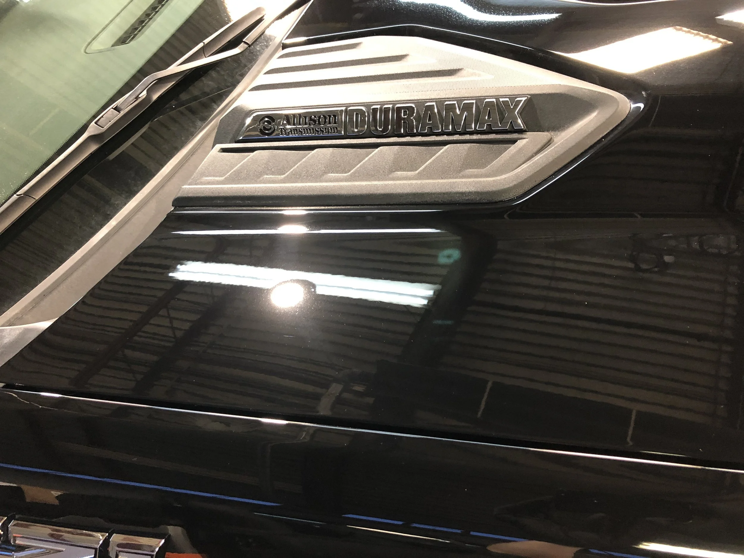 Close-up of a black Ford Bronco emblem with a Duramax badge and Allison transmission badge on the side of the vehicle.