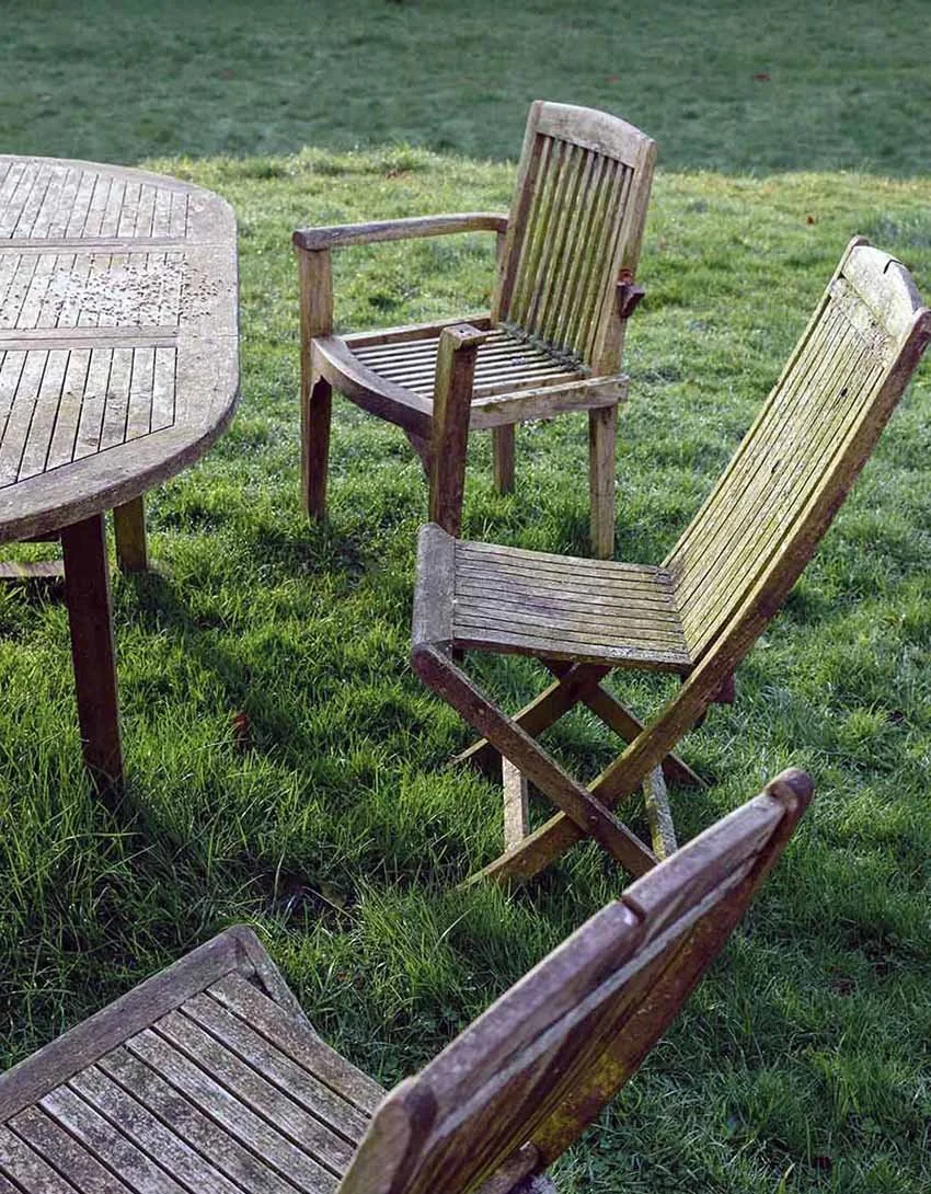 Spiritual Direction Training Weathered wooden outdoor chairs and a table on a grassy lawn.