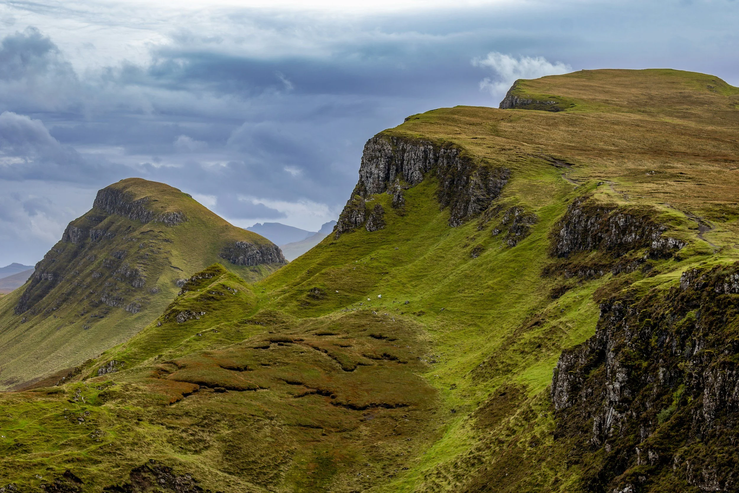Green grassy hills and mountains under a cloudy sky.