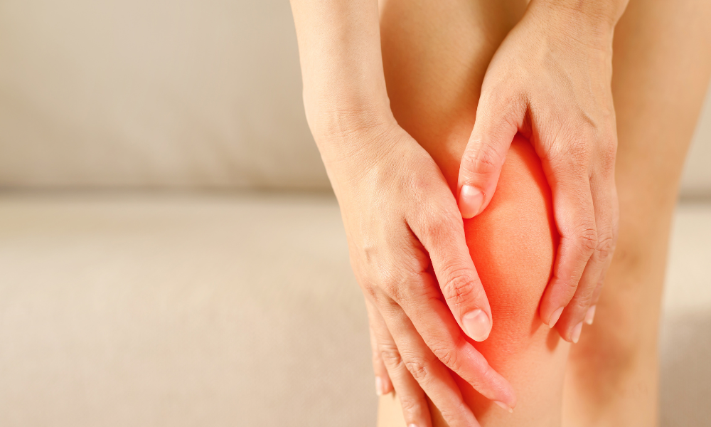 Close-up of hands holding a knee with a red glow, indicating joint pain or discomfort.