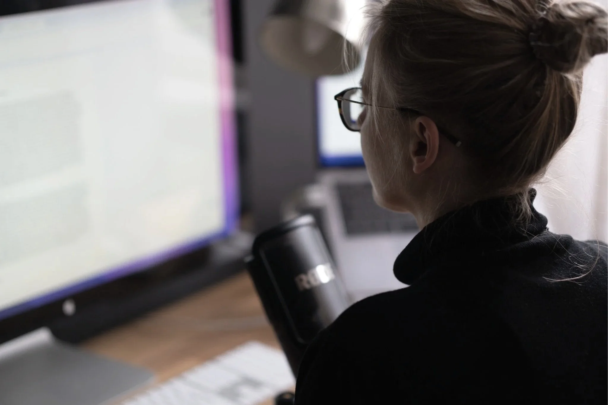 Close-up of Dr Kat sitting at her desk speaking into a microphone and recording a podcast