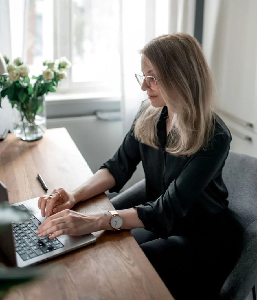 Dr Kat sitting at her desk working on her laptop, looking at the screen and typing on the keyboard of her laptop.
