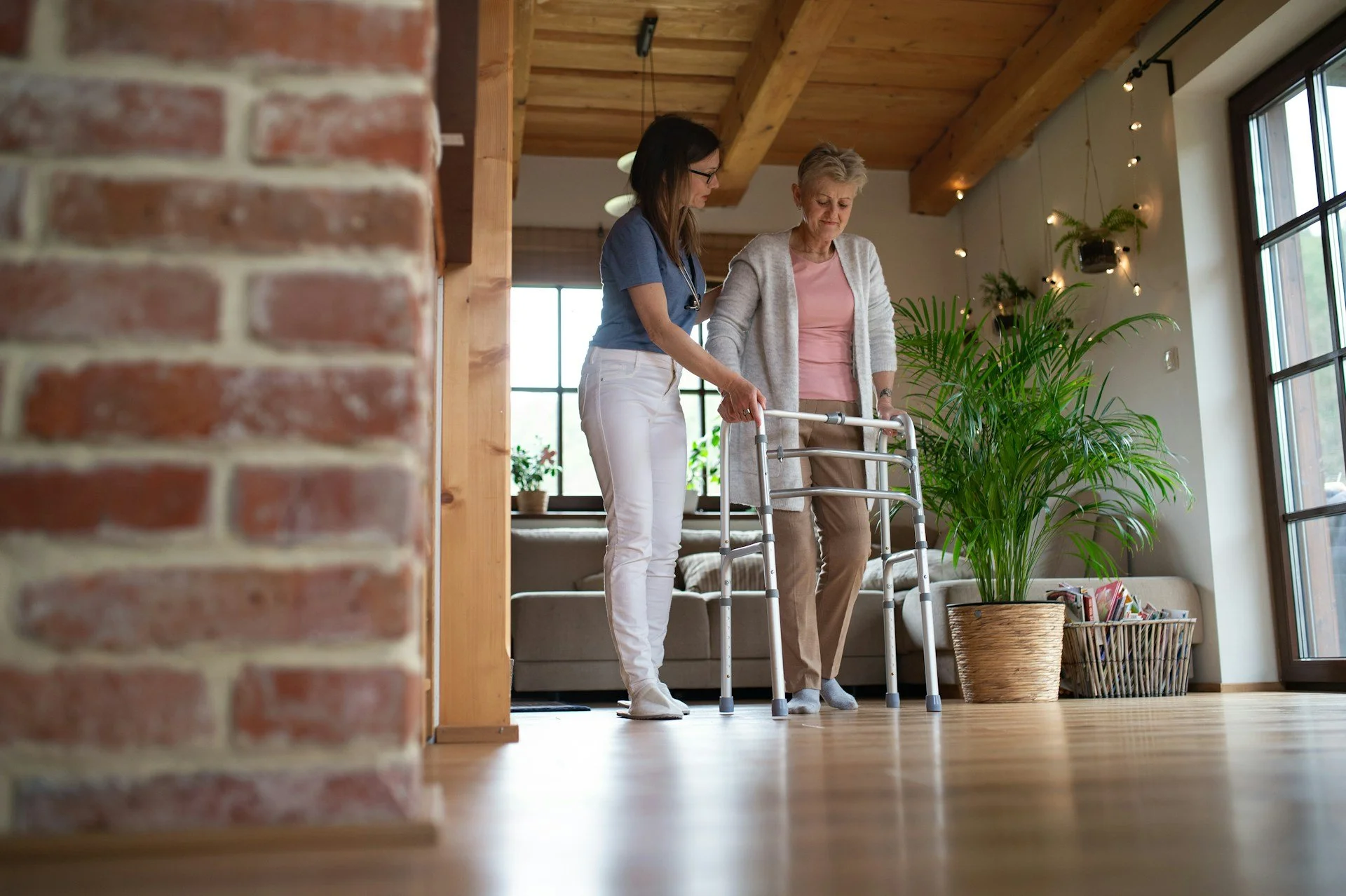 A caregiver helps her patient walk with a walker in her home
