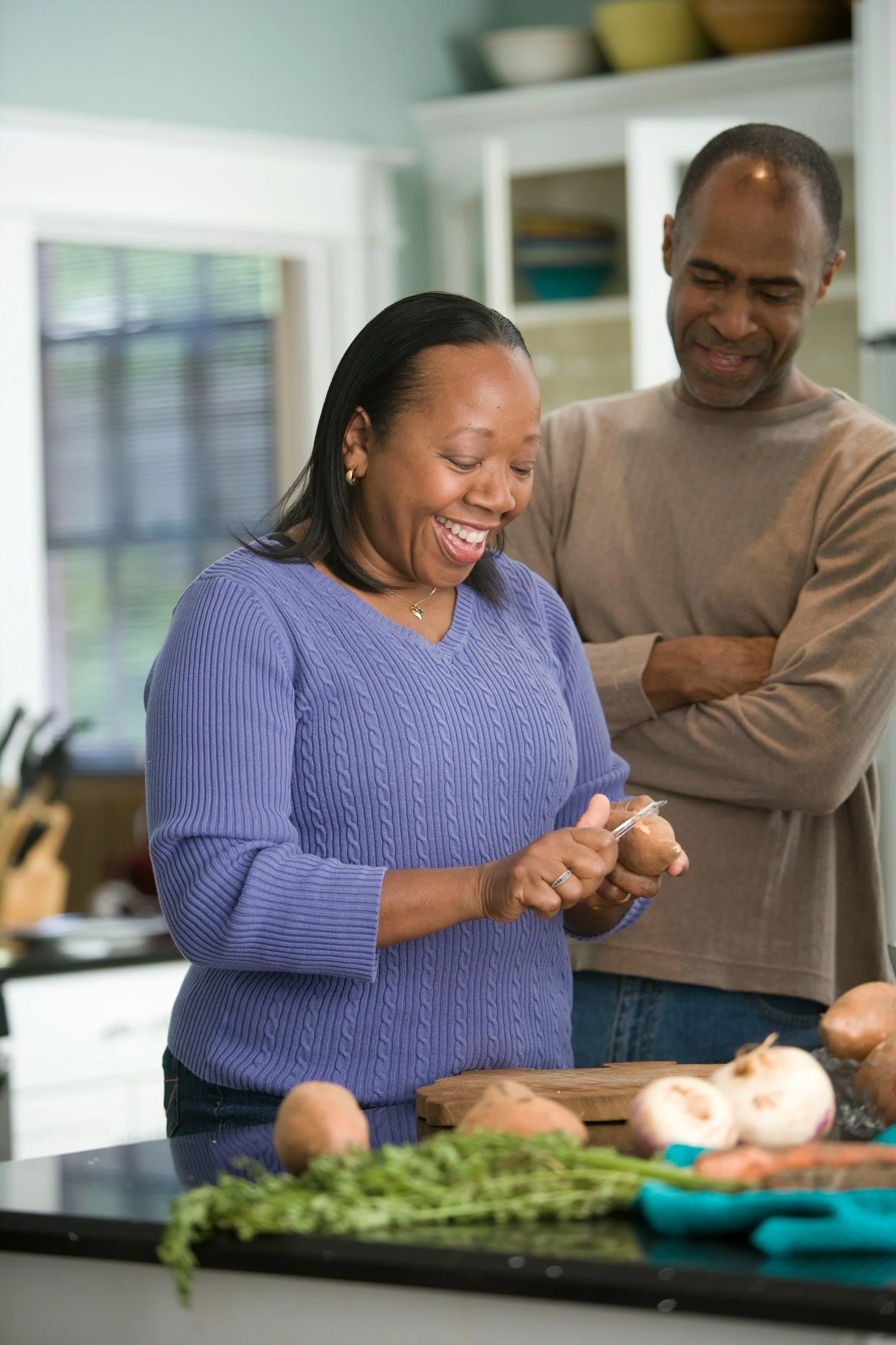 A man and a  woman share a smile as they prepare food in the kitchen