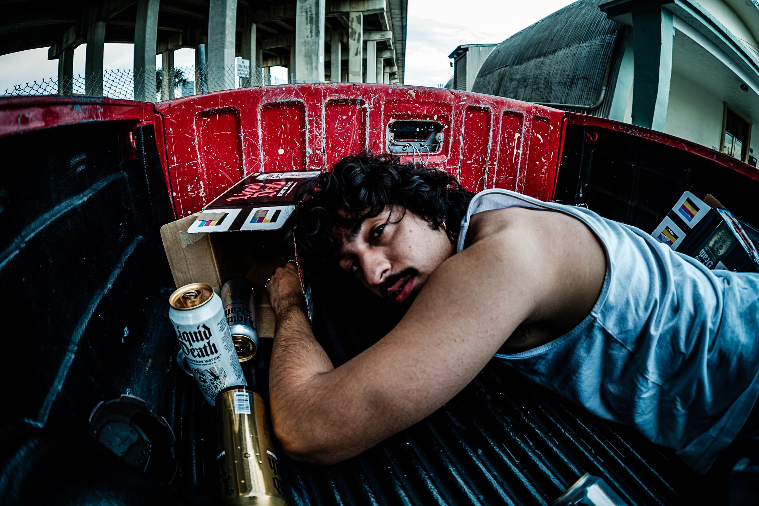 An acquaintance of mine, José, was an aspiring model, doing a shoot together I noticed he had several cases of Liquid Death in the cab of his truck. We decided to do some photos as if he "had too much to drink" and passed out in his truck bed. 

Abou