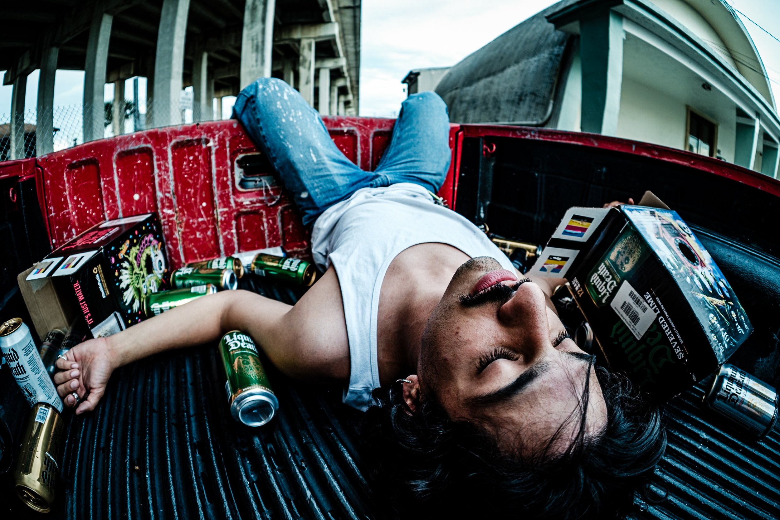 An acquaintance of mine, José, was an aspiring model, doing a shoot together I noticed he had several cases of Liquid Death in the cab of his truck. We decided to do some photos as if he "had too much to drink" and passed out in his truck bed. 

Abou