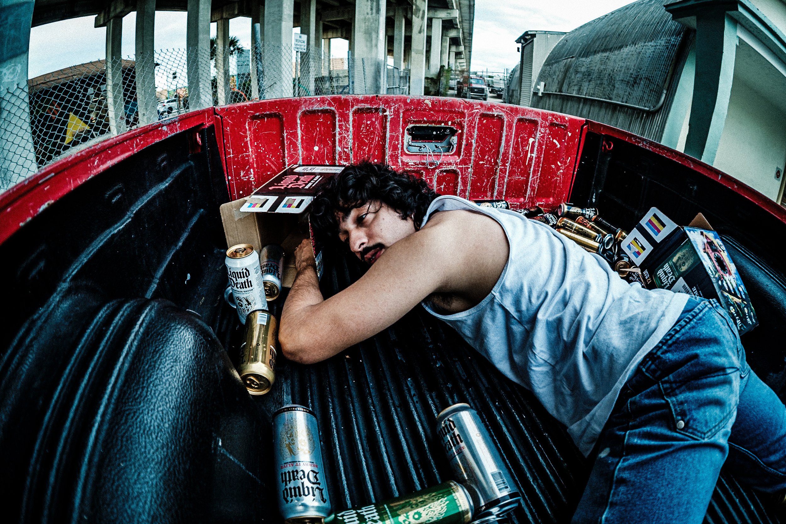 An acquaintance of mine, José, was an aspiring model, doing a shoot together I noticed he had several cases of Liquid Death in the cab of his truck. We decided to do some photos as if he "had too much to drink" and passed out in his truck bed. 

Abou