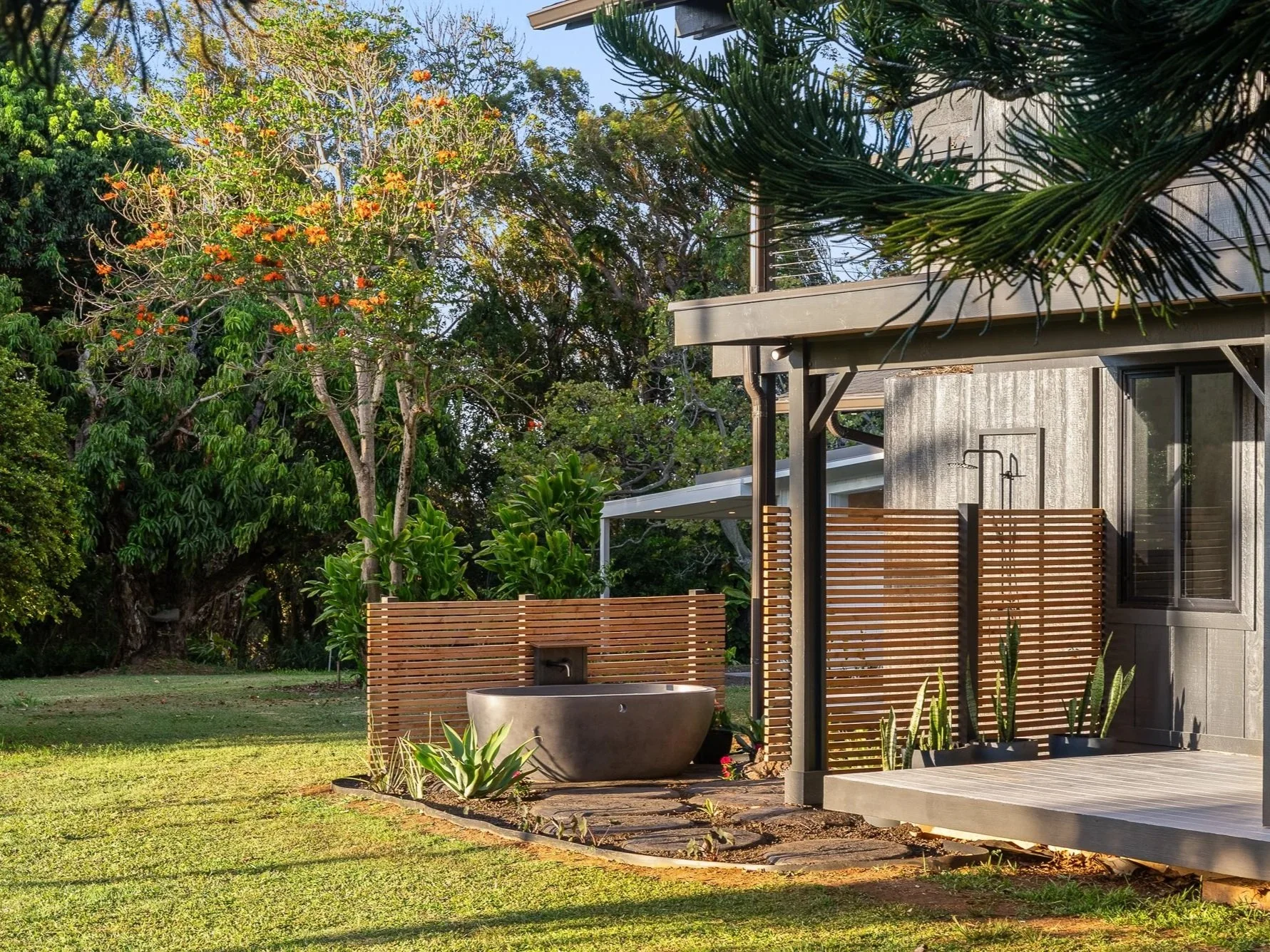 Outdoor bathtub surrounded by tropical greenery at a private Maui residence, presented by Eva Besselmann.