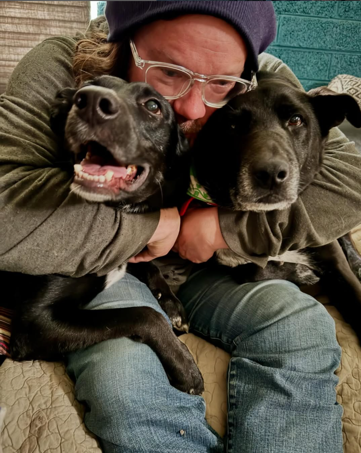 man with two black dogs