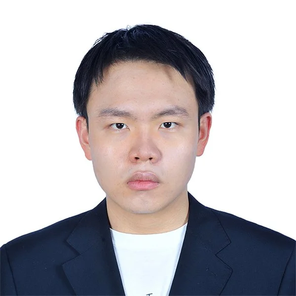 Headshot of a young Asian man with short black hair, wearing a dark blazer over a white shirt, against a plain white background.