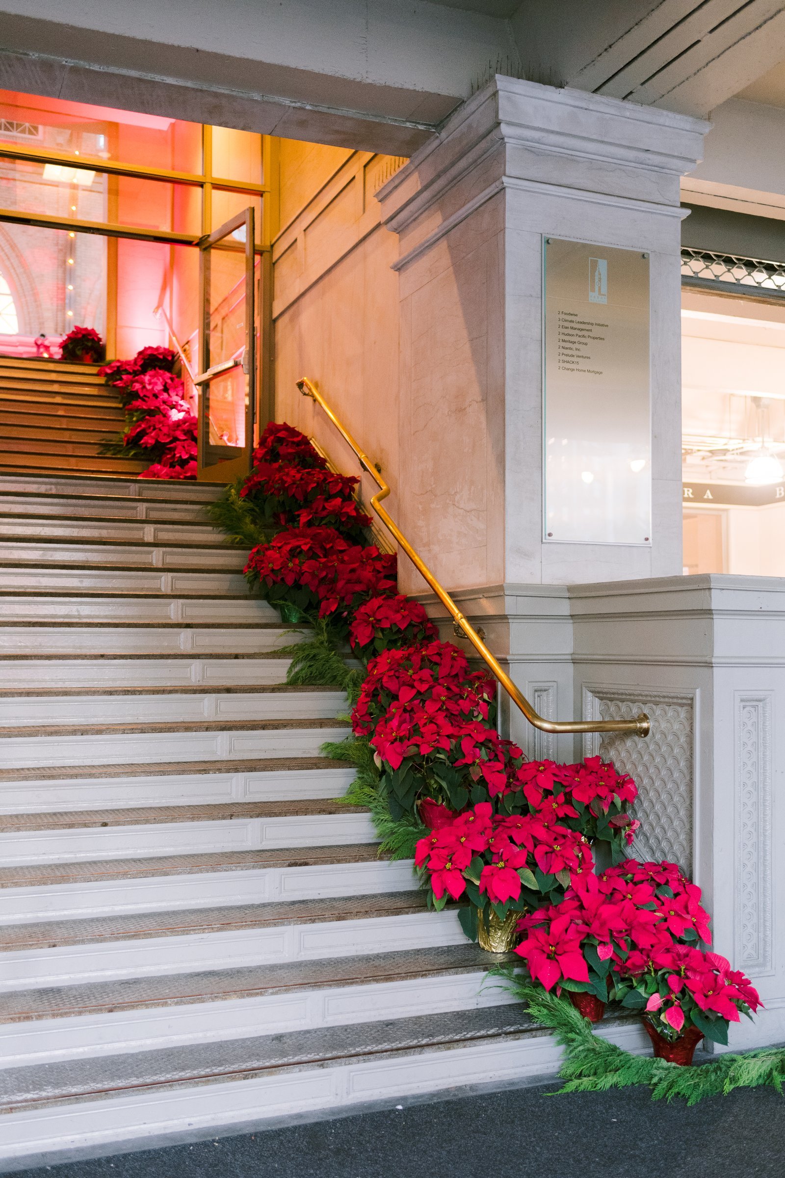 bay-area-corporate-holiday-party-poinsettia-staircase-entrance-holiday-party-cedar-garland-brass-handrail-san-francisco.jpg