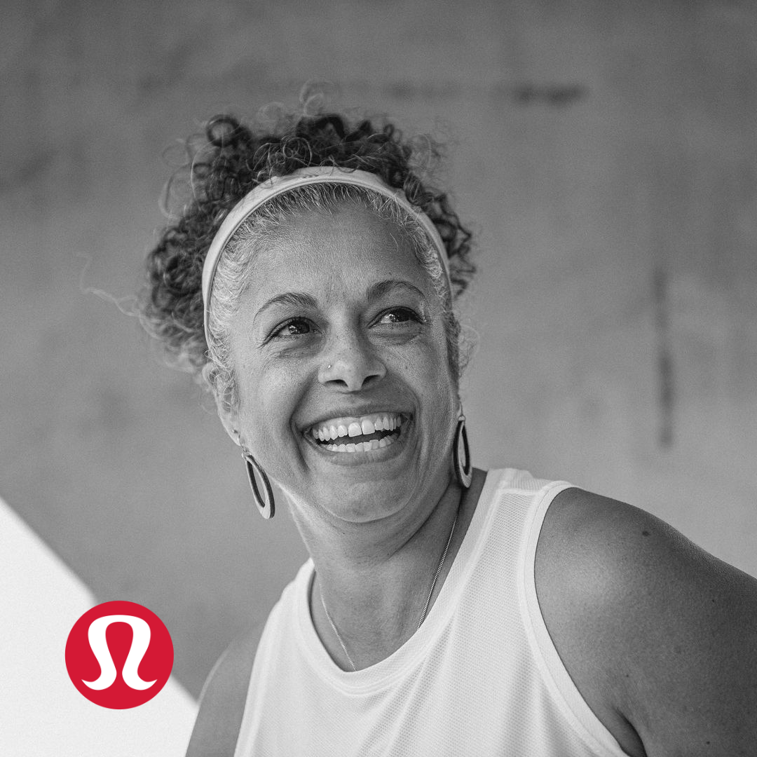 A smiling woman with curly hair, wearing a headband, earrings, and athletic clothing, with the Lululemon logo in the bottom left corner.