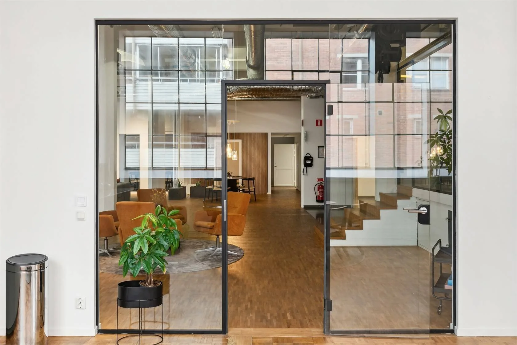 Interior view of a modern office space with glass walls, stairs, and seating areas.