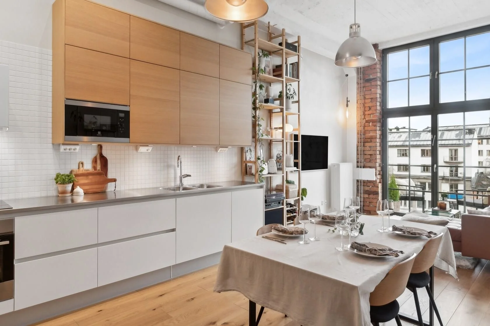 Open-concept kitchen and living area with large window, dining table set for four, and modern decor.