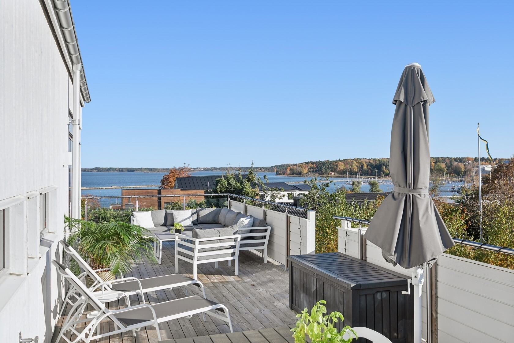 Decorated outdoor balcony with seating and view of water and trees in the distance.