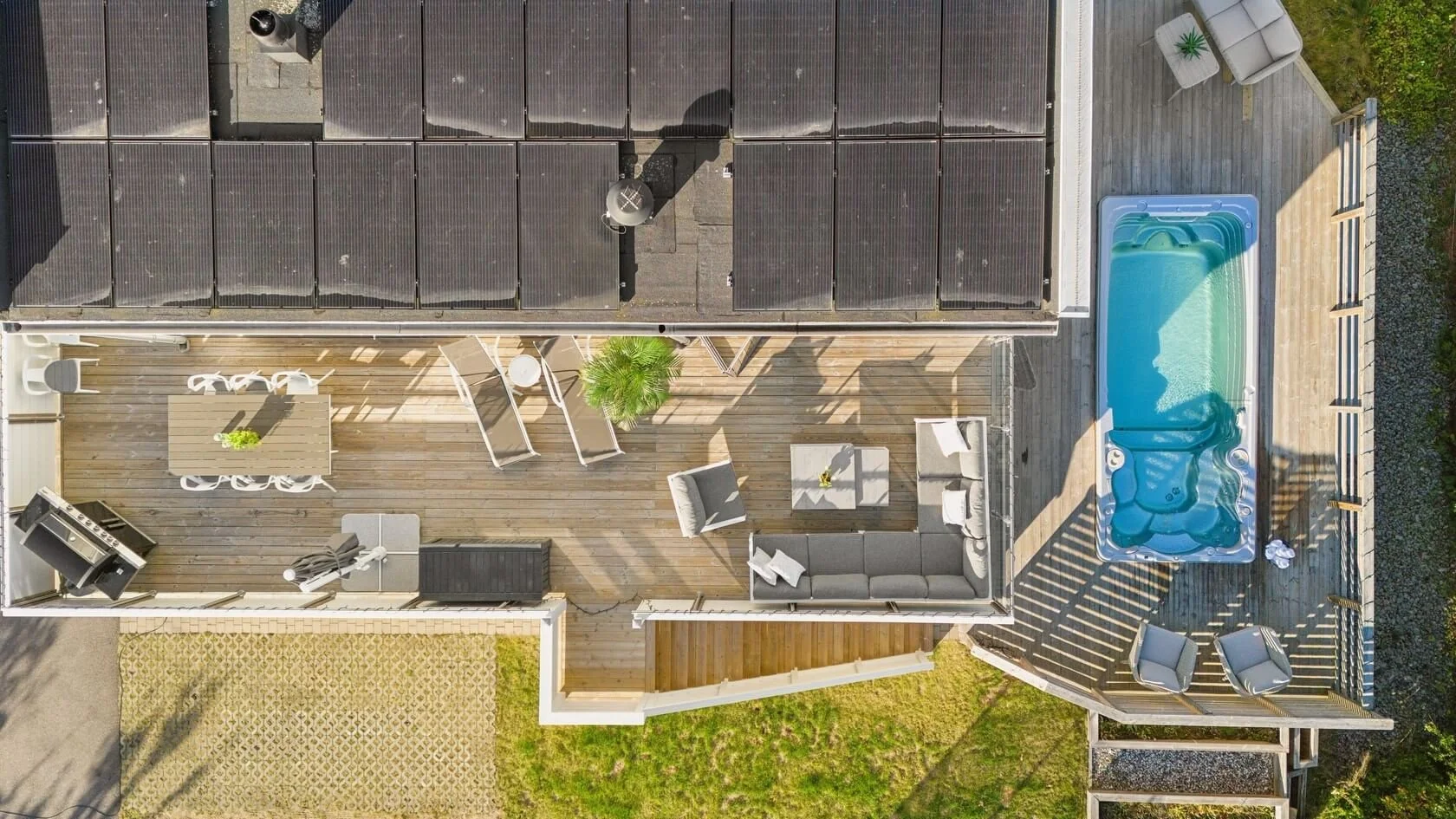 Aerial view of a house backyard deck with outdoor furniture, a small pool, a barbecue grill, and a garden area.