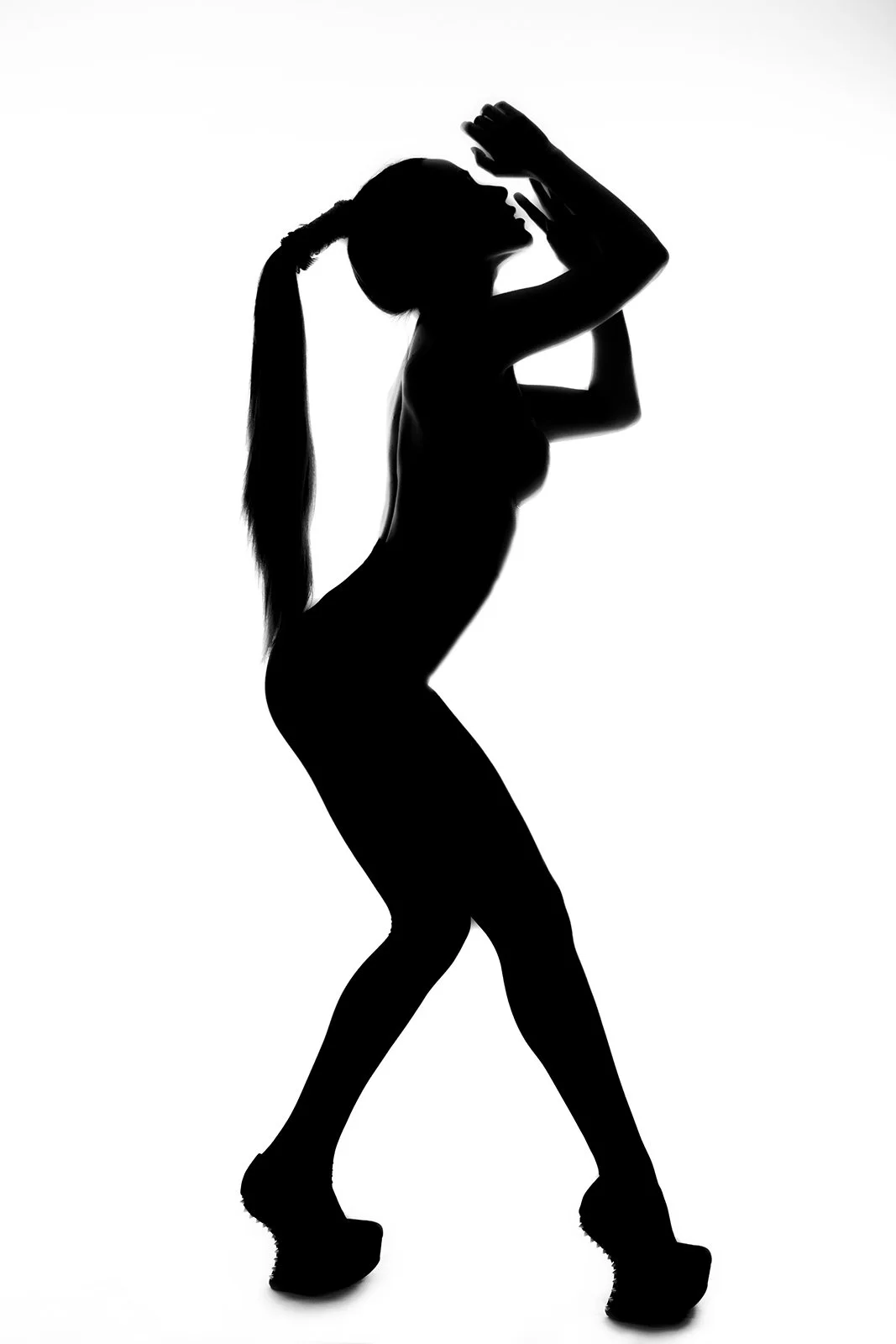 Silhouette of a woman with a long ponytail posing with one hand near her face and the other on her head against a white background.