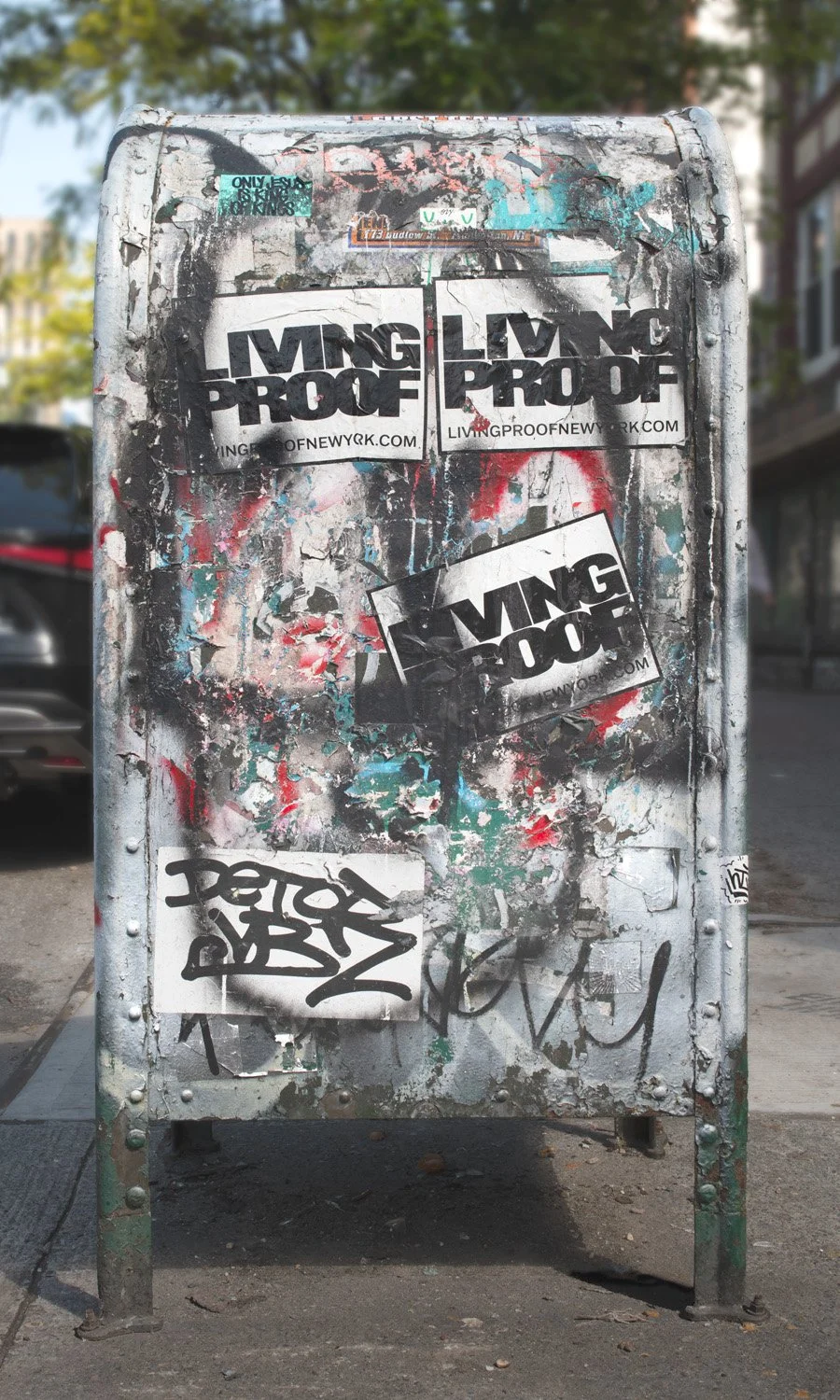 Fine art urban photography print of a public New York City mailbox covered in sticker slaps and graffiti. This photograph of street art collage is captured by contemporary photographer Barton Lewis.