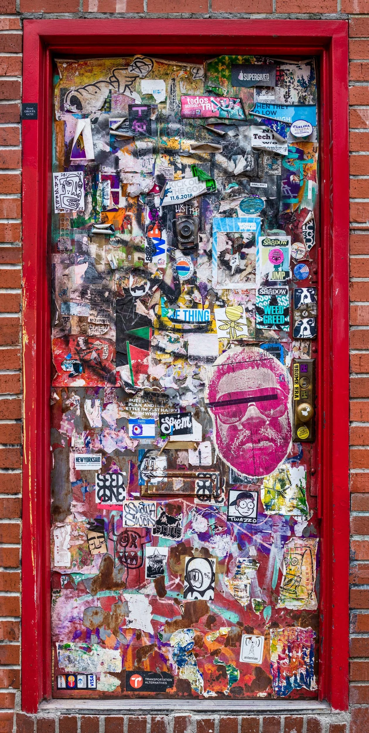 Fine art urban photography print of a door in New York City entirely covered in layers of sticker slaps. This example of collaborative and impromptu street art is captured by contemporary photographer Barton Lewis.
