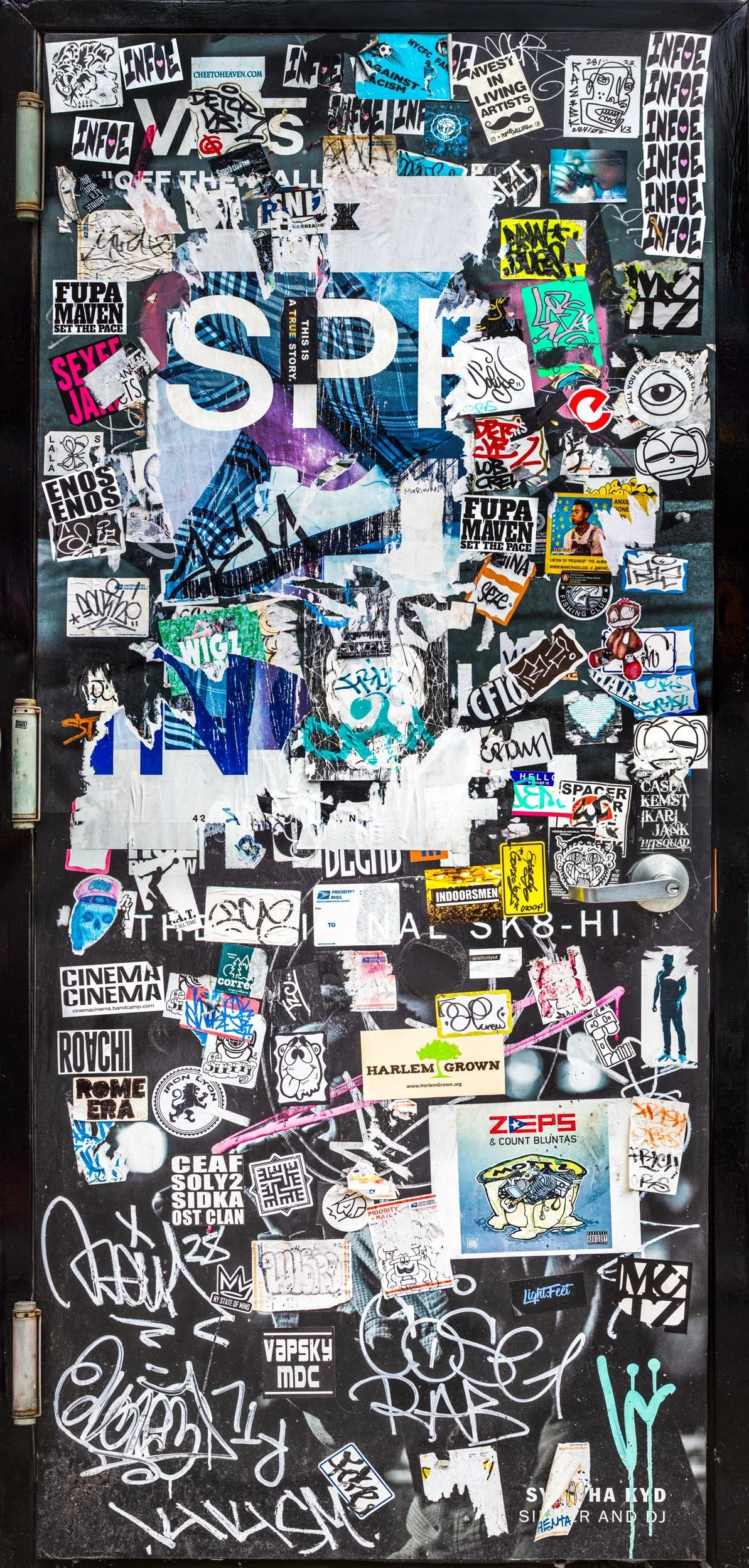 Fine art urban photography print of a door in New York City entirely covered in layers of sticker slaps. This example of collaborative and impromptu street art is captured by contemporary photographer Barton Lewis.