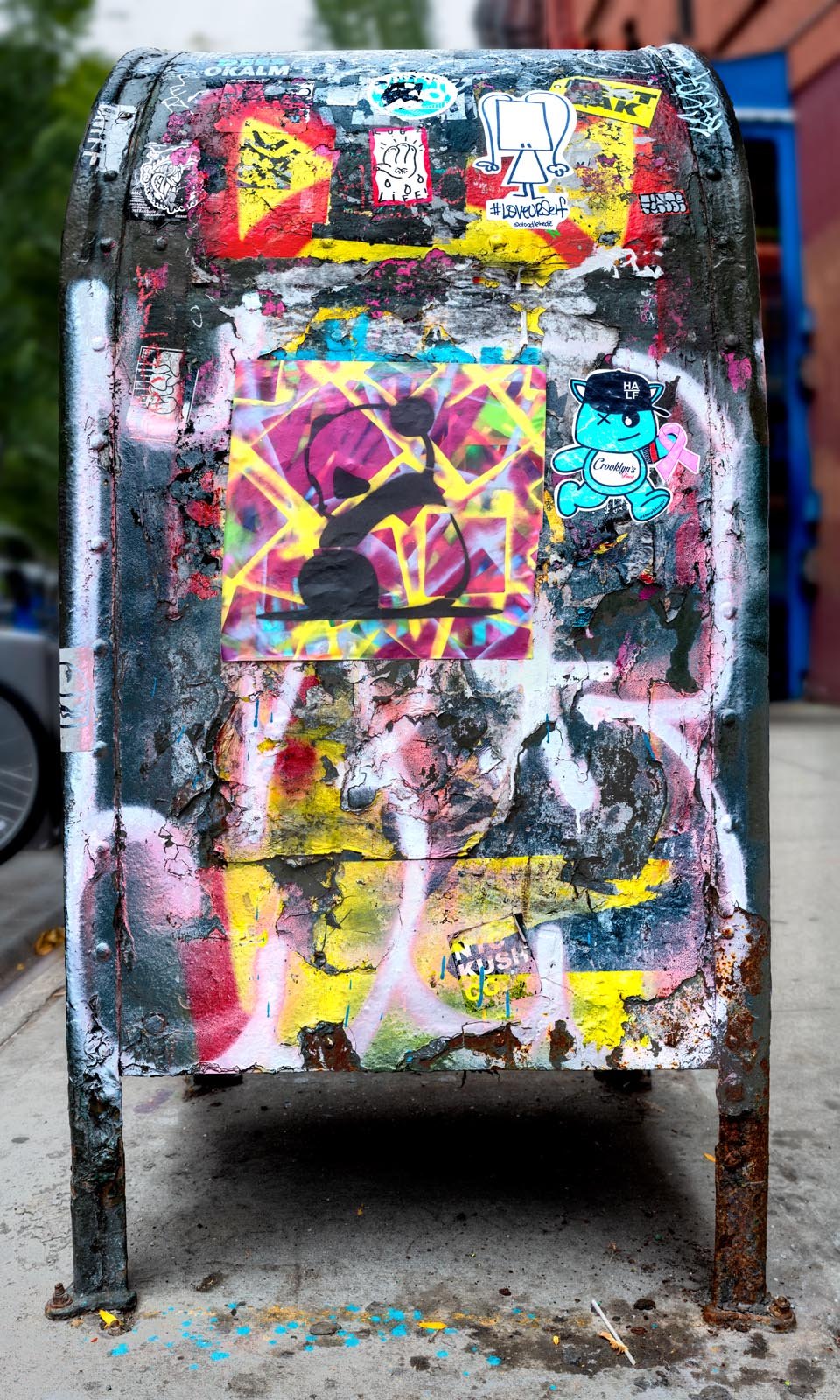 Fine art urban photography print of a public New York City mailbox covered in sticker slaps and graffiti. This photograph of street art collage is captured by contemporary photographer Barton Lewis.