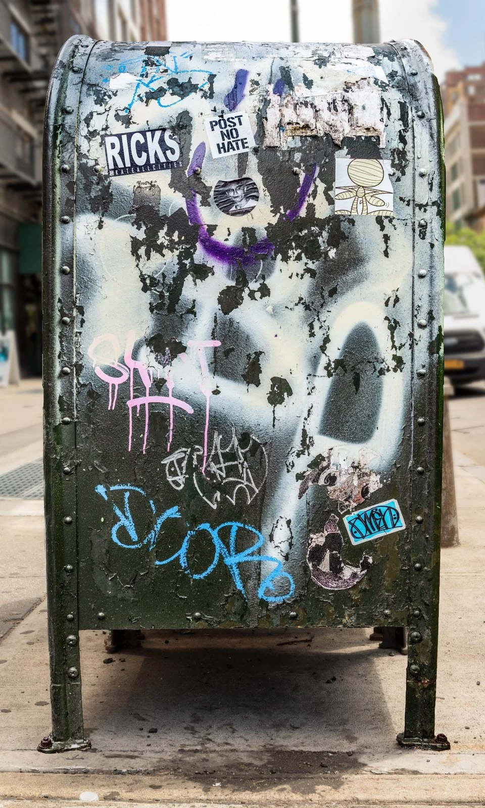 Fine art urban photography print of a public New York City mailbox covered in sticker slaps and graffiti. This photograph of street art collage is captured by contemporary photographer Barton Lewis.