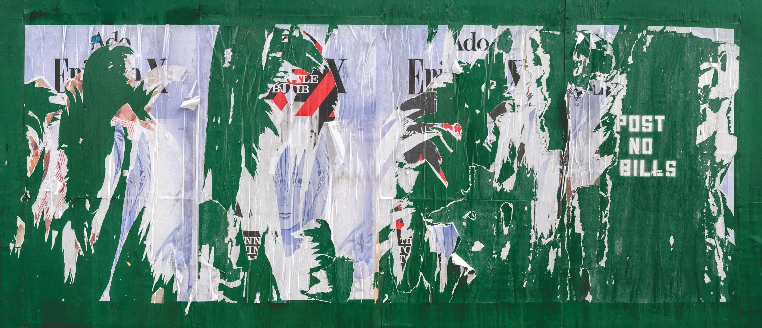 Fine art urban photography capturing decaying advertising posters on a plywood construction site fence. The composition isolates layers of shredded commercial paper, weathered textures, and accidental street art by Barton Lewis.