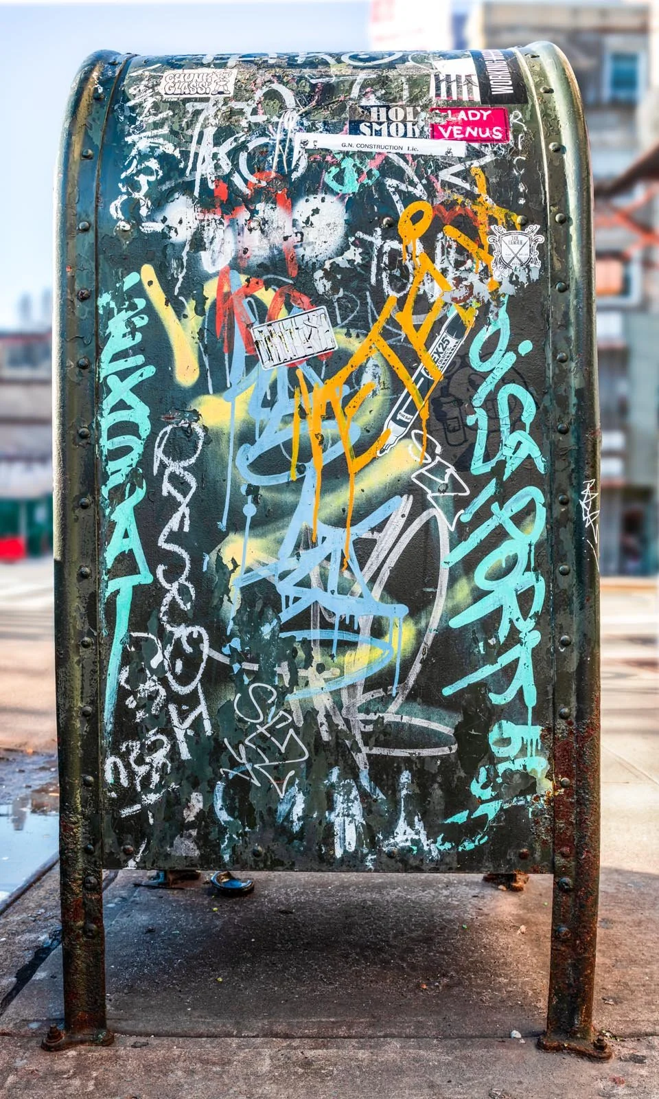 Fine art urban photography print of a public New York City mailbox covered in sticker slaps and graffiti. This photograph of street art collage is captured by contemporary photographer Barton Lewis.