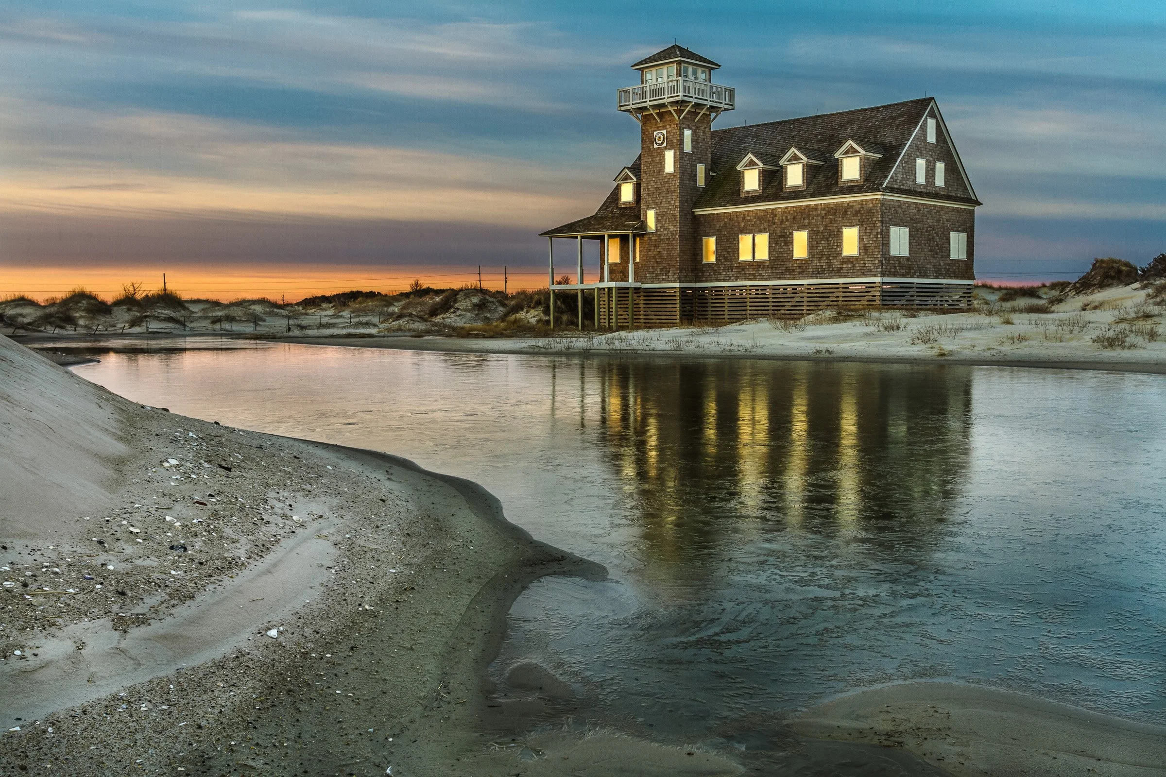Frozen sunrise reflection in front of the Pea Island Lifesaving Station on a winter morning.