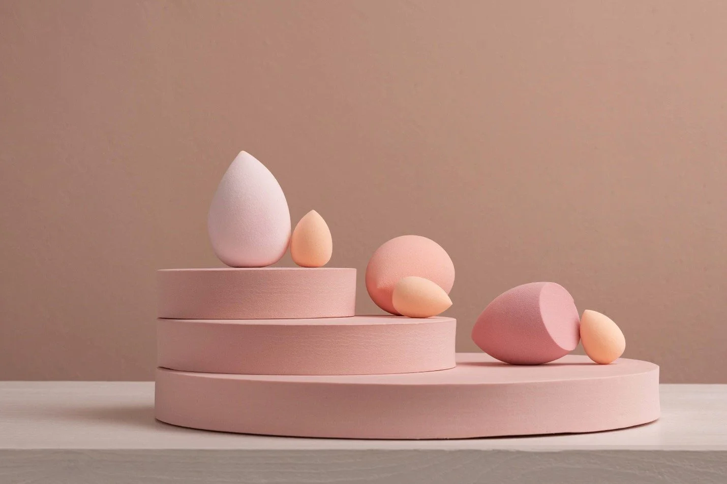 Decorative pastel-colored eggs and spheres on a pink tiered display with a neutral background
