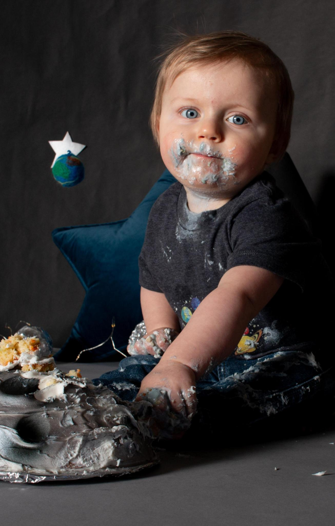 Toddler boy with frosting on his face during a 1st birthday cake smash portrait session in Cincinnati