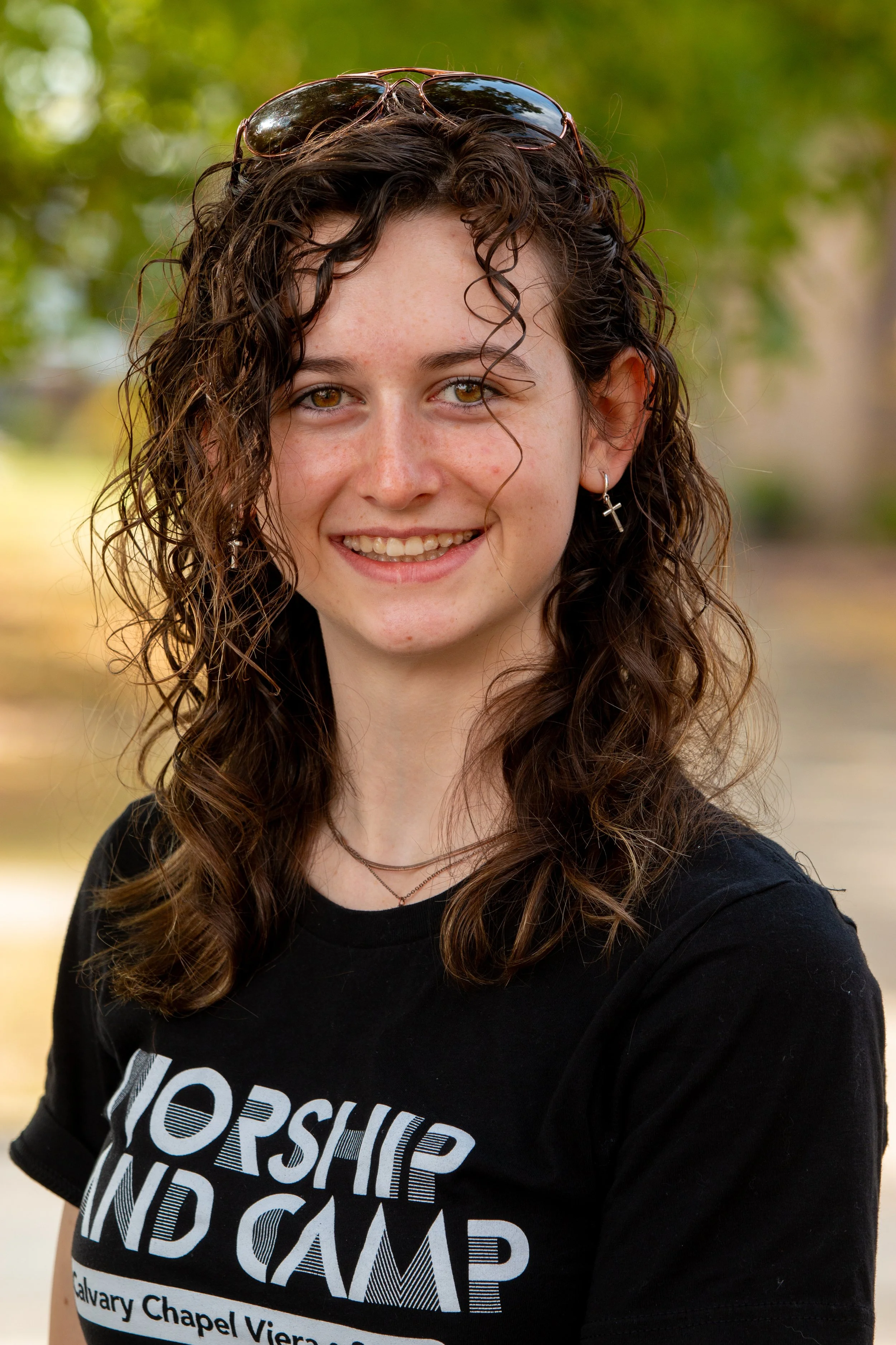 Student portrait with natural expression and outdoor greenery background during school picture day