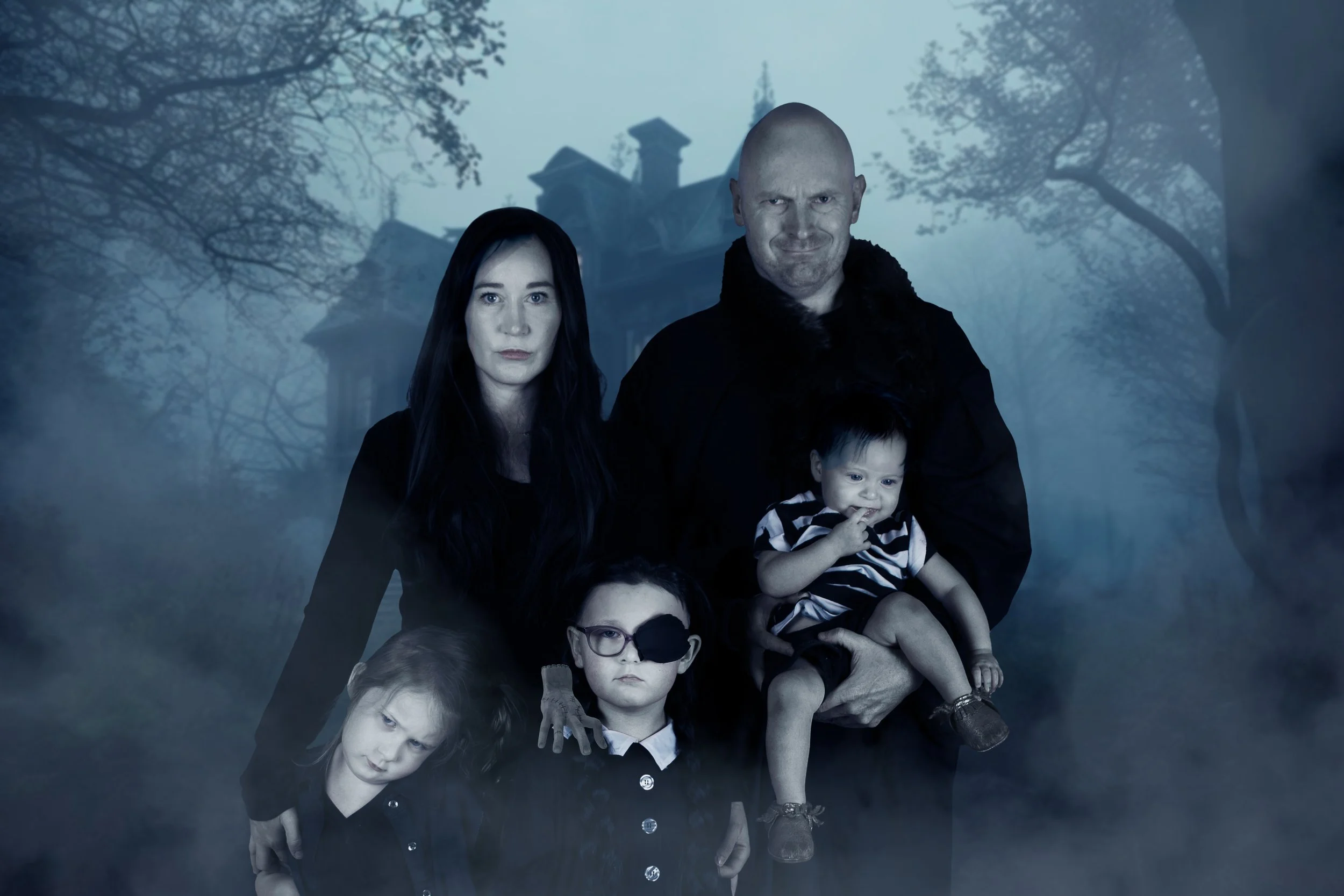 Creative Addams Family themed family portrait with spooky fog and haunted house backdrop at Say Yes to Jess