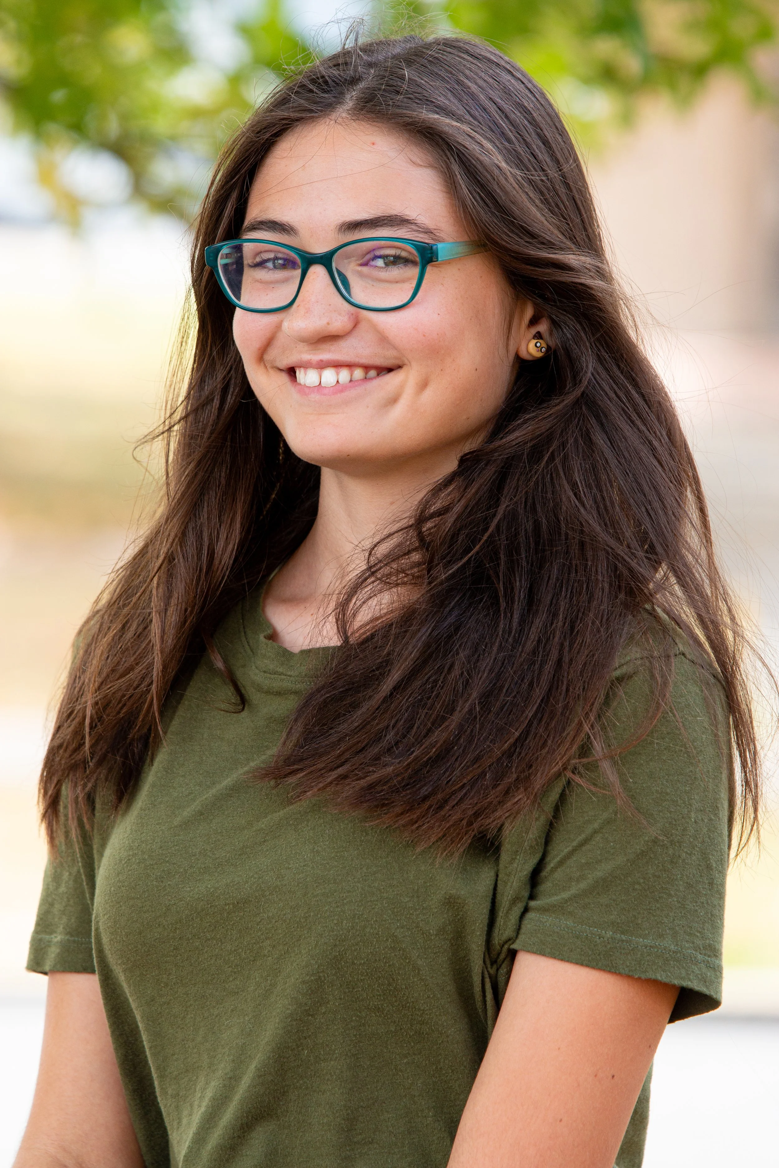 Student with teal glasses smiling for outdoor school portrait with natural light