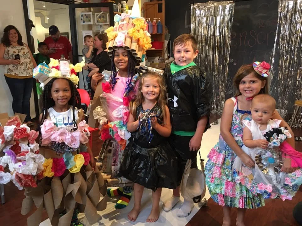 Group of kids posing in their handmade recycled outfits at the Say Yes to Jess trashion show at Red Balloon Cafe in Cincinnati