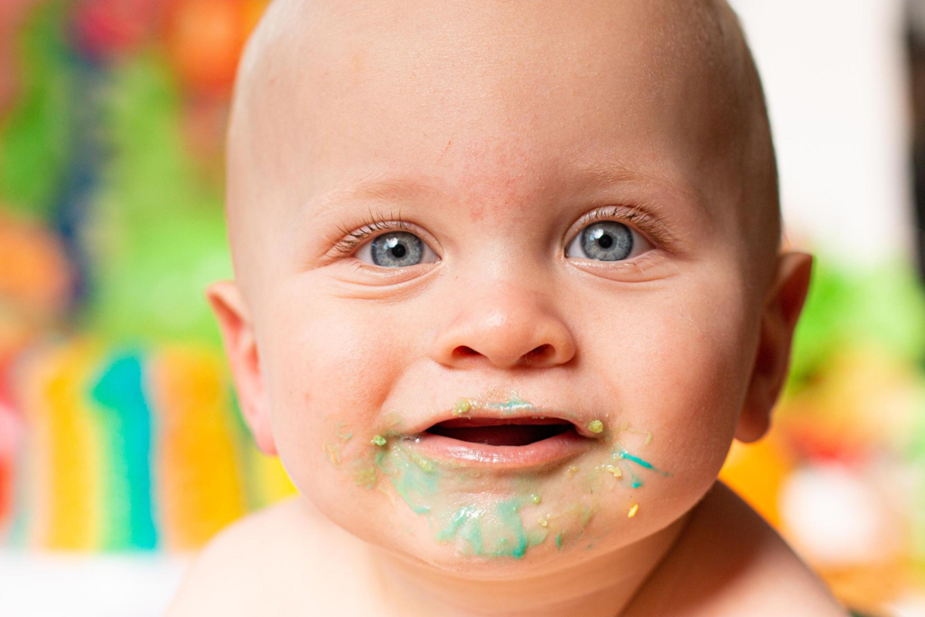 Close-up of a baby's frosting-covered face during a 1st birthday cake smash at Say Yes to Jess