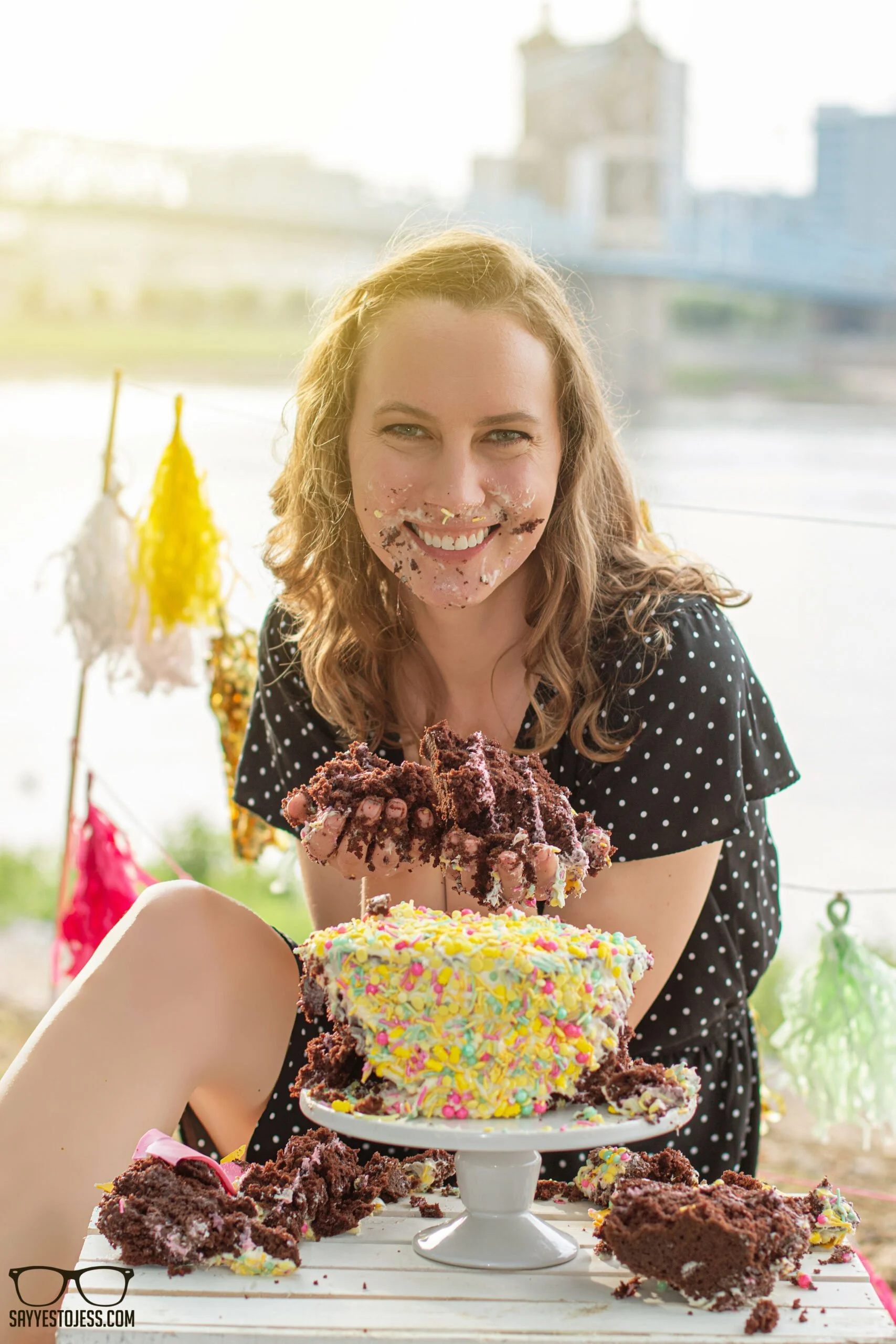 Woman laughing with cake all over her face during an adult cake smash session on the Cincinnati riverfront