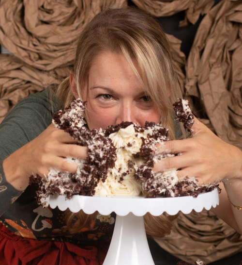 Woman taking a huge bite of chocolate cake during an adult cake smash session at Say Yes to Jess in Cincinnati