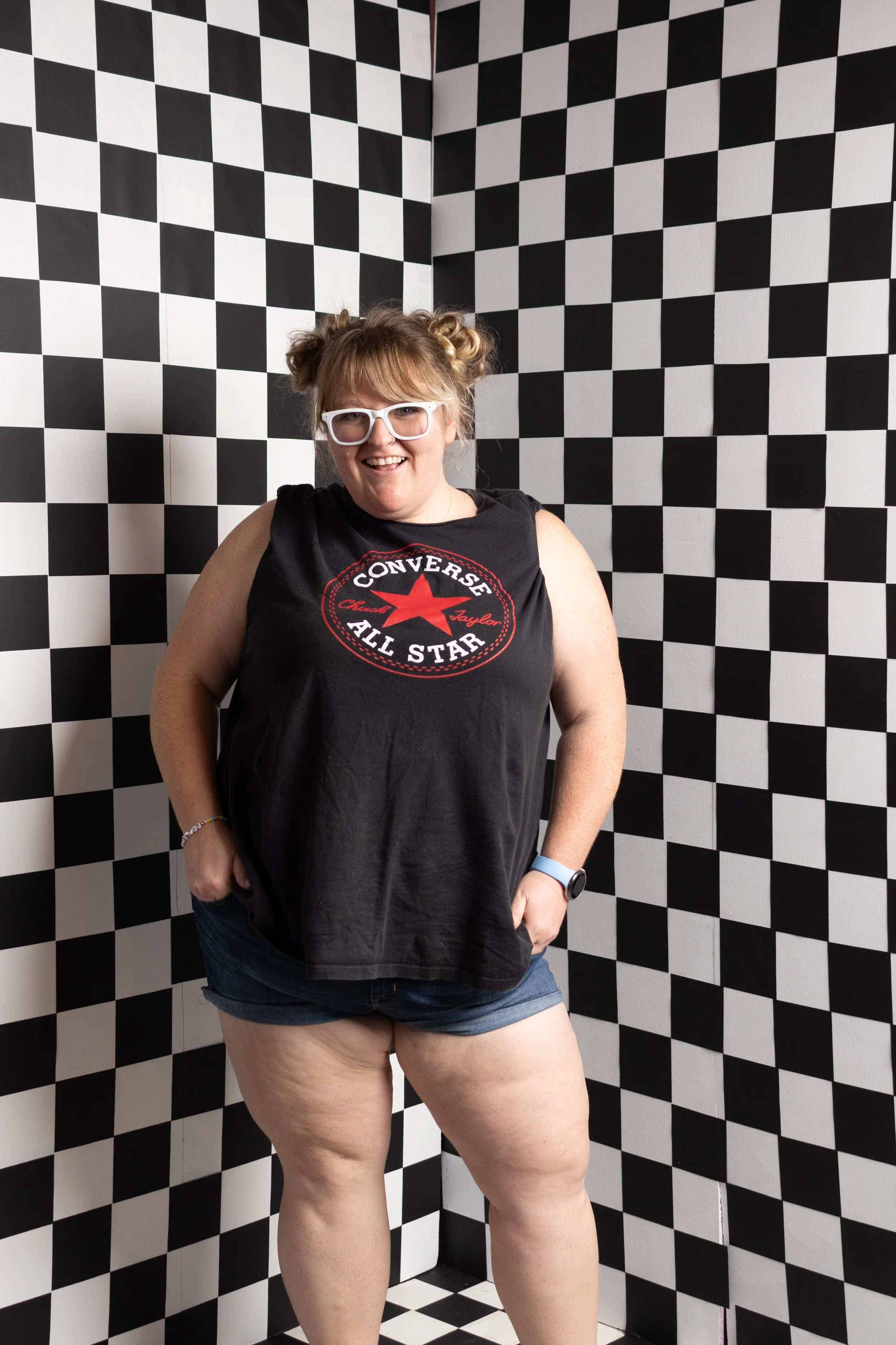 Cincinnati photographer Jess Summers with space buns posing in the black and white checkerboard set at Say Yes to Jess studio for Mother's Day mini sessions