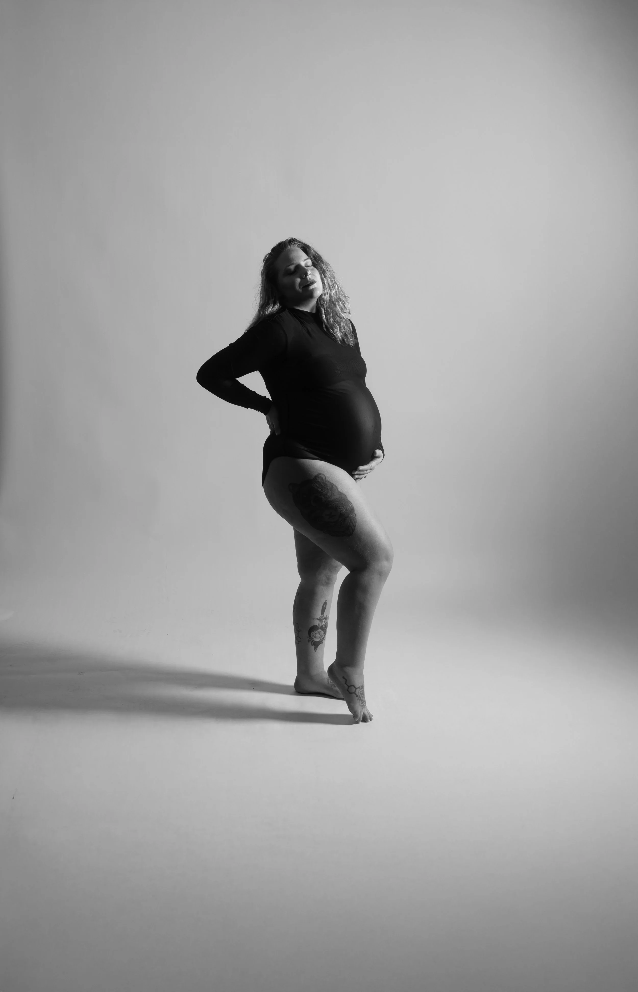 Creative maternity portrait session featuring expecting mother posing in studio with professional lighting