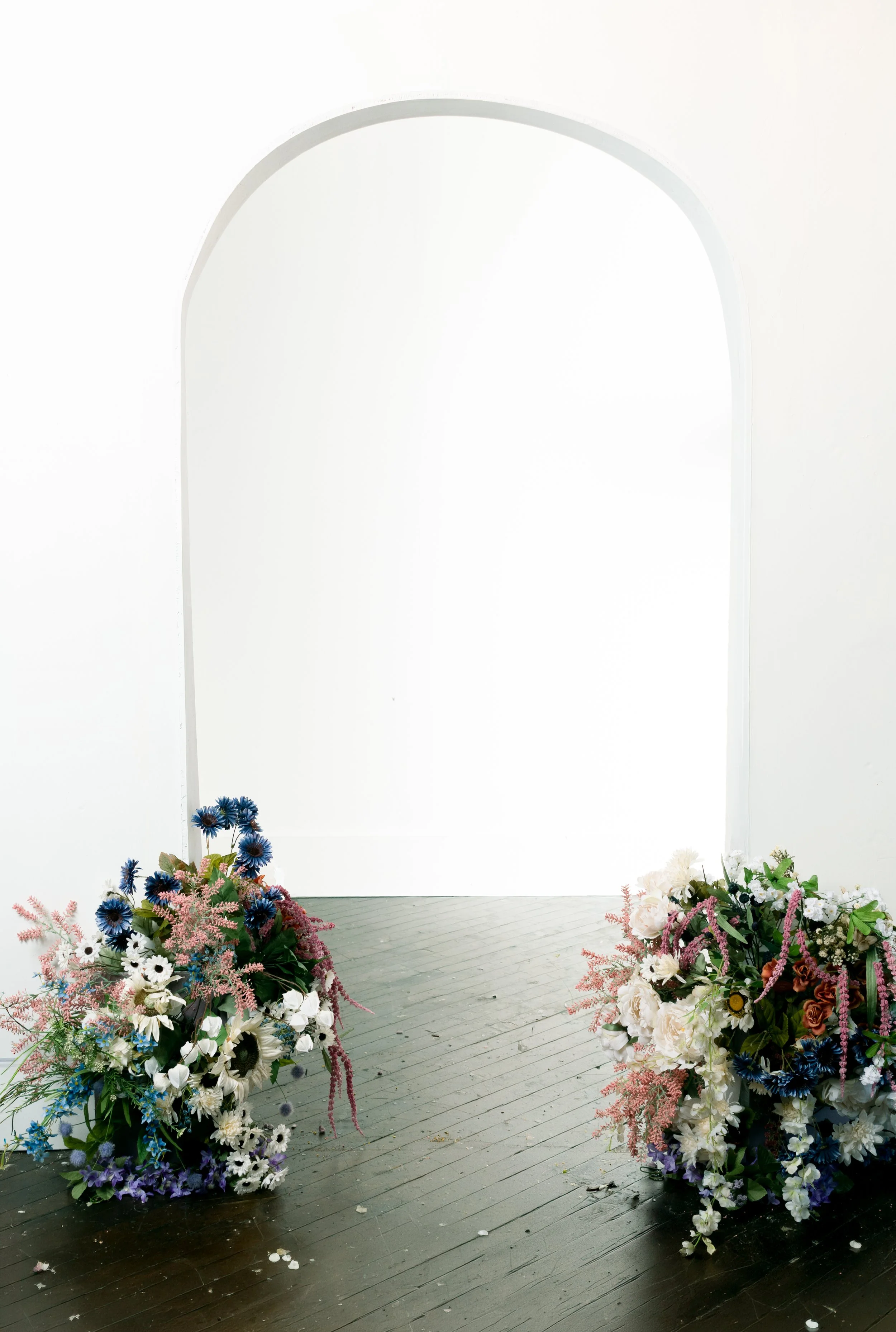 Custom hand-built white arch doorway photography set with floral arrangements at the base for Mother's Day mommy and me mini sessions at Say Yes to Jess studio in Cincinnati